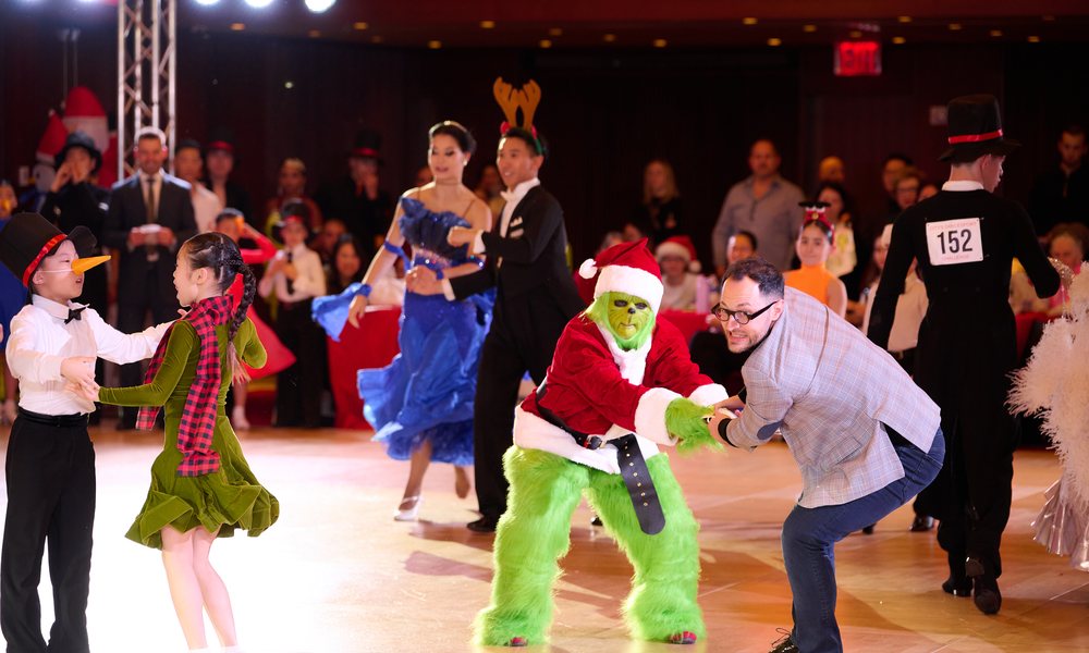 A costumed Grinch dancing with a child on the floor at City&rsquo;s Dancesport Challenge
